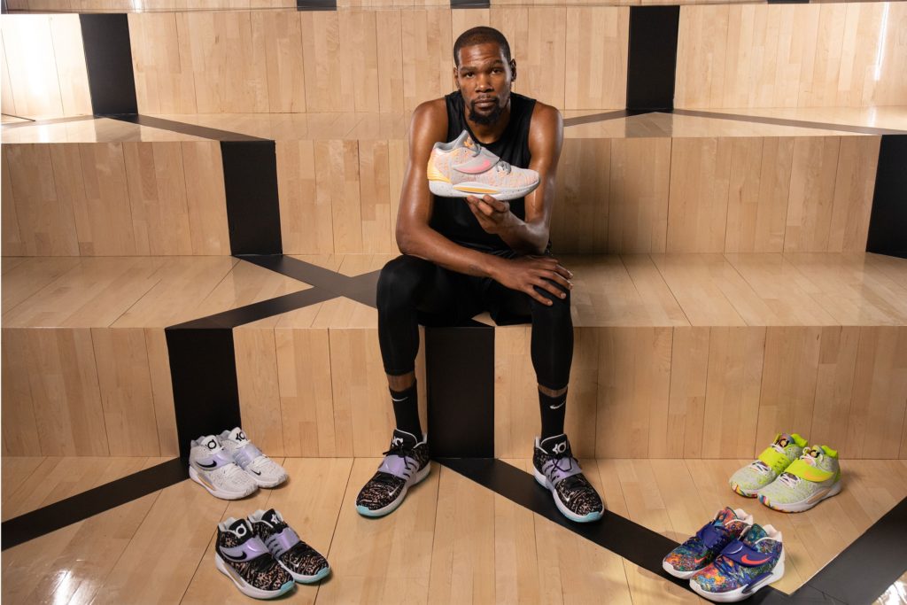 Kevin Durant sitting with multiple colorways of the Nike KD14