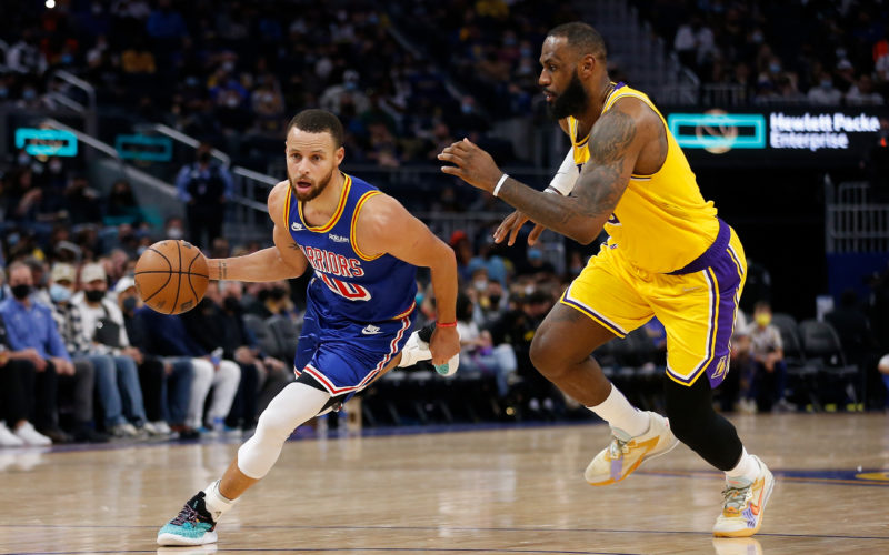 Basketball player Stephen Curry dribbling the ball while LeBron James plays defense against him
