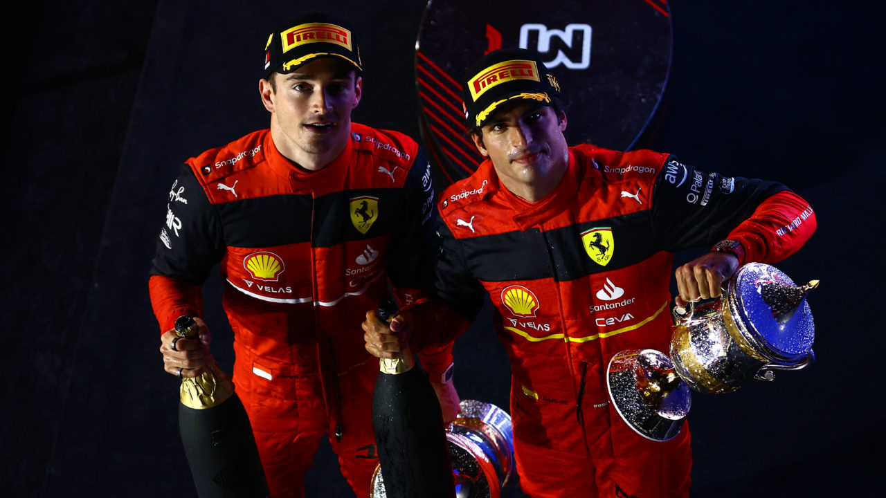 Ferrari race drivers Charles Leclerc and Carlos Sainz looking upward with champagne bottles celebrating their top-two finish in the F1 Bahrain GP