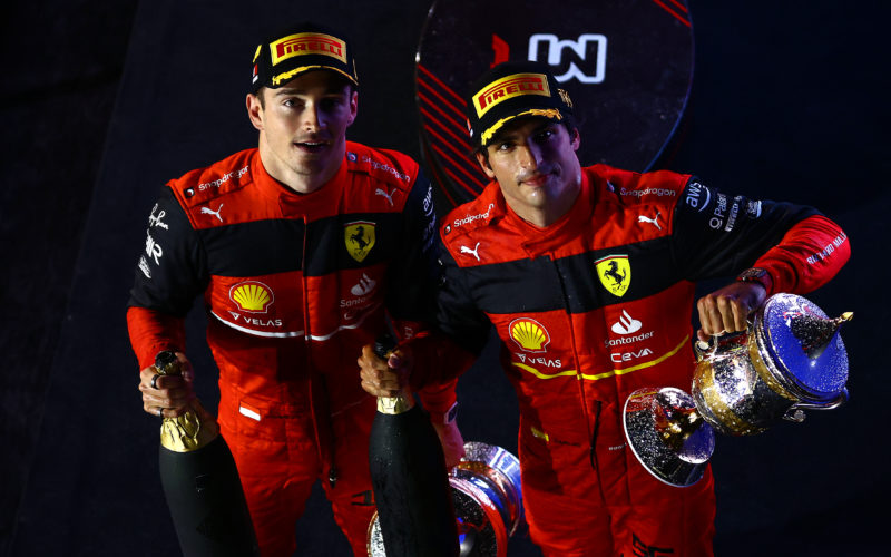 Ferrari race drivers Charles Leclerc and Carlos Sainz looking upward with champagne bottles celebrating their top-two finish in the F1 Bahrain GP