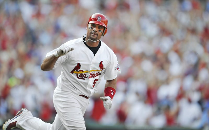 Baseball player Albert Pujols pumping a fist while running around the bases following a home run