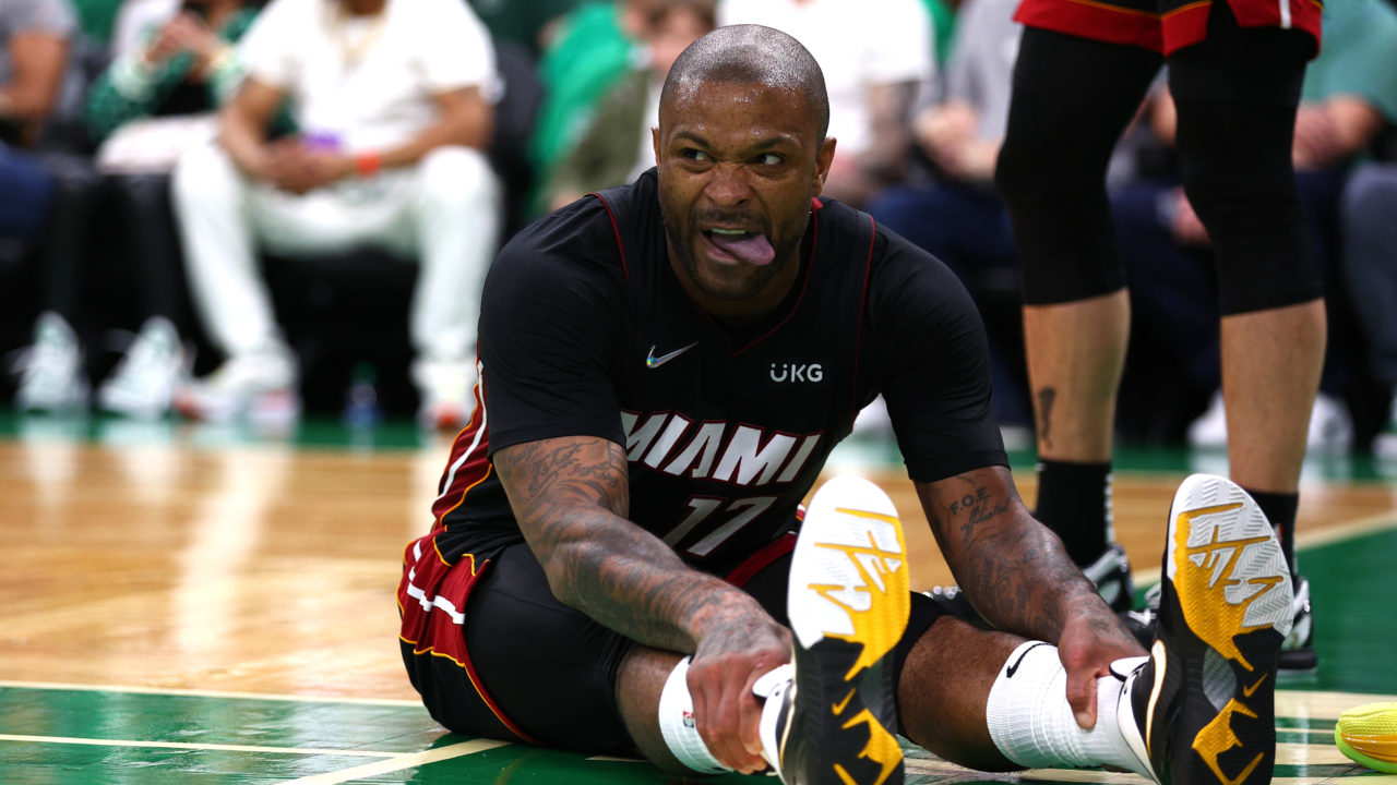 Basketball player PJ Tucker sitting down on a basketball court with his legs extended forward before a game