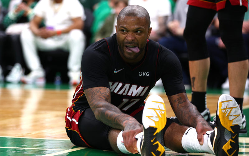 Basketball player PJ Tucker sitting down on a basketball court with his legs extended forward before a game