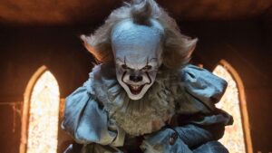 Actor Bill Skarsgard posing and grinning as Pennywise in the 2017 film "It"